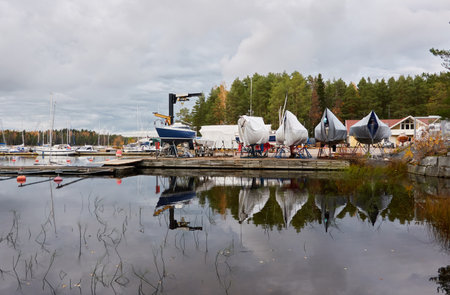 Sailboats moored to a pier and standing on land in a yacht marina prepared for winterization or new sailing season. Transportation, repair and service conceptsの写真素材