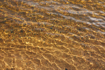 Crystal clear water surface texture. River or lake. Sand, stones or pebbles. Soft sunlight. Natural pattern, background, graphic resources. Pure nature, environment conceptsの写真素材