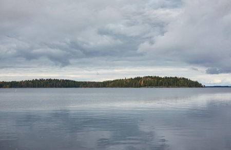 Forest lake (river) on a cloudy day. Reflections in water. Dramatic sky. Glowing clouds after the rain. Finland. Idyllic autumn landscape. Pure nature, ecology, ecological reserve, ecotourismの写真素材