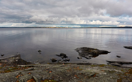 Forest lake (river) on a cloudy day. Reflections in water. Dramatic sky. Glowing clouds after the rain. Finland. Idyllic autumn landscape. Pure nature, ecology, ecological reserve, ecotourismの写真素材