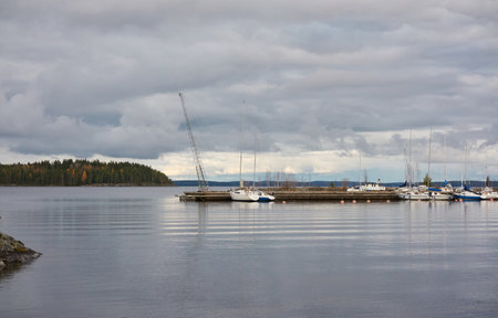 Sailboats moored to a pier and standing on land in a yacht marina prepared for winterization or new sailing season. Transportation, repair and service conceptsの写真素材