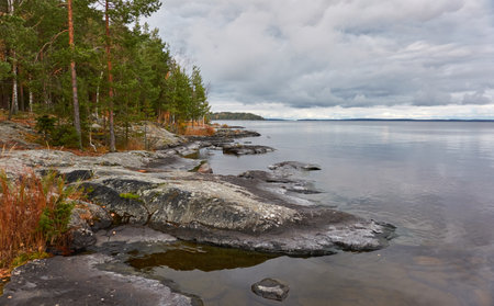 Forest lake (river) on a cloudy day. Reflections in water. Dramatic sky. Glowing clouds after the rain. Finland. Idyllic autumn landscape. Pure nature, ecology, ecological reserve, ecotourismの写真素材