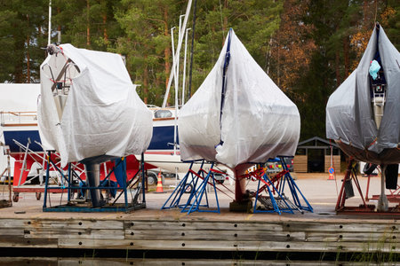 Sailboats standing on land in a yacht marina prepared for winterization or new sailing season. Transportation, repair and service conceptsの写真素材