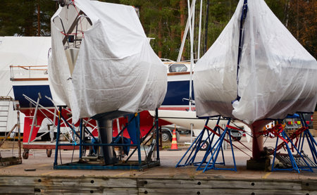 Sailboats standing on land in a yacht marina prepared for winterization or new sailing season. Transportation, repair and service conceptsの写真素材