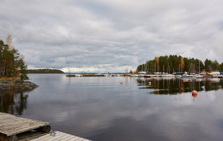 Sailboats moored to a pier and standing on land in a yacht marina prepared for winterization or new sailing season. Transportation, repair and service conceptsの写真素材