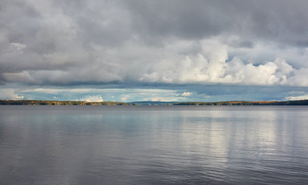 Forest lake (river) on a cloudy day. Reflections in water. Dramatic sky. Glowing clouds after the rain. Finland. Idyllic autumn landscape. Pure nature, ecology, ecological reserve, ecotourismの写真素材