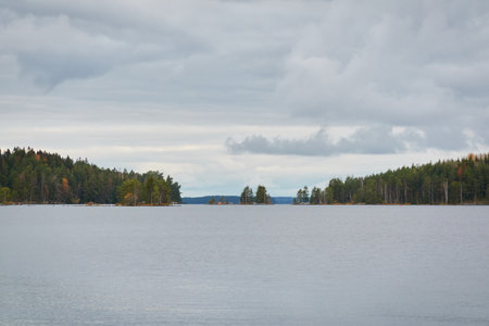 Forest lake (river) on a cloudy day. Reflections in water. Dramatic sky. Glowing clouds after the rain. Finland. Idyllic autumn landscape. Pure nature, ecology, ecological reserve, ecotourismの写真素材