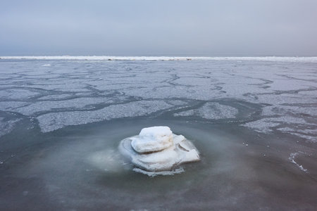 A view from the frozen snow-covered Baltic sea shore. cloudy day. Crystal clear water, cracked ice....