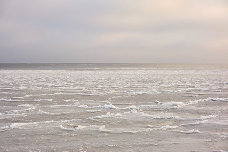 A view from the frozen snow-covered Baltic sea shore. cloudy day. Crystal clear water, cracked ice....