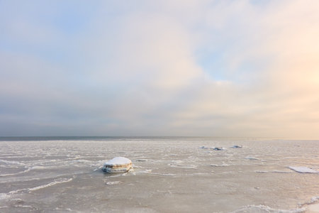 Snow-covered Baltic sea shore at sunrise.Snow, ice, frozen water. soft sunlight. picturesque winter scenery. Seasons, nature, environment, climate change, global warming themesの写真素材