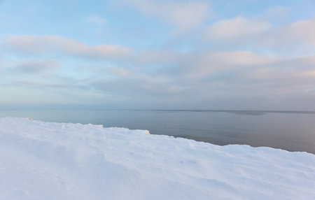 Snow-covered Baltic sea shore at sunrise.Snow, ice, frozen water. soft sunlight. picturesque winter scenery. Seasons, nature, environment, climate change, global warming themesの写真素材