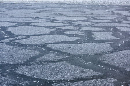 Cracked ice and water surface, frozen sea shore, texture, close-up. picturesque winter scenery. Concept image, graphic resources. Seasons, nature, ecology, environment, climate change, global warmingの写真素材