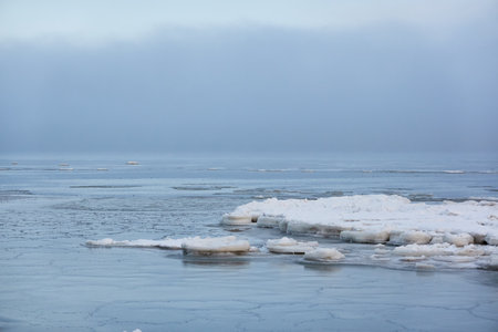 A view from the frozen snow-covered Baltic sea shore. cloudy day. Crystal clear water, cracked ice....