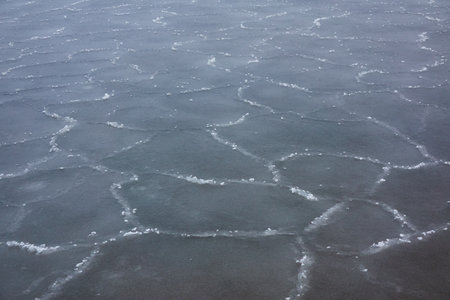Cracked ice and water surface, frozen sea shore, texture, close-up. picturesque winter scenery. Concept image, graphic resources. Seasons, nature, ecology, environment, climate change, global warmingの写真素材
