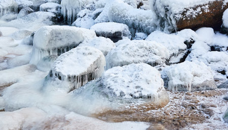 Frozen sea water surface texture, stones, icicles. Cloudy day, Ice, snow. Fickle weather, blizzard. Winter, global warming, climate change, ecology themesの写真素材