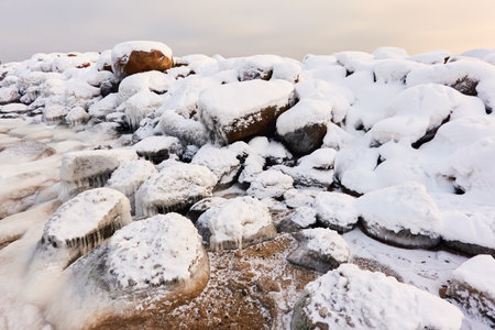 Frozen sea, stones, icicles. Cloudy day, Ice, snow. Fickle weather, blizzard. Winter, global warming, climate change, ecology themesの写真素材