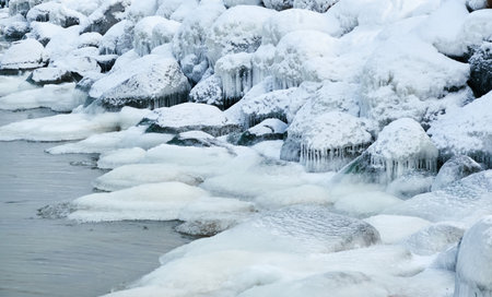 Frozen sea, stones, icicles. Cloudy day, Ice, snow. Fickle weather, blizzard. Winter, global warming, climate change, ecology themesの写真素材