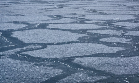 Cracked ice and water surface, frozen sea shore, texture, close-up. picturesque winter scenery. Concept image, graphic resources. Seasons, nature, ecology, environment, climate change, global warmingの写真素材