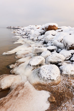 Frozen sea water surface texture, stones, icicles. Cloudy day, Ice, snow. Fickle weather, blizzard. Winter, global warming, climate change, ecology themesの写真素材
