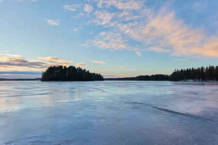Panoramic view of the forest lake on a sunny winter day. evergreen trees. soft sunlight. Frozen water surface. Finland. Environment, nature, ecology, ecotourism, cold weather, climate change themesの写真素材