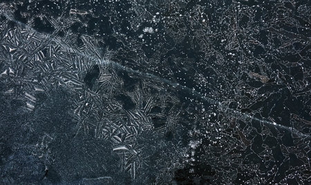 Cracked ice, snowflakes, snow, dark water surface, frozen lake shore. texture, close-up. picturesque winter scenery. Concept image, graphic resources. Nature, ecology, climate change, global warmingの写真素材