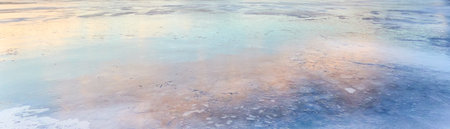 Cracked ice, snowflakes, snow, water surface, frozen lake shore. Sunset or sunrise. texture, close-up. winter scenery. Concept image, graphic resources. Nature, ecology, climate, global warmingの写真素材