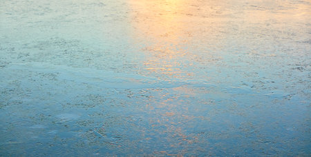 Cracked ice, snowflakes, snow, water surface, frozen lake shore. Sunset or sunrise. texture, close-up. winter scenery. Concept image, graphic resources. Nature, ecology, climate, global warmingの写真素材