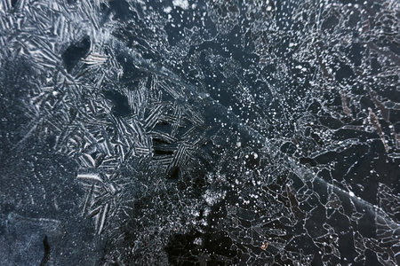 Cracked ice, snowflakes, snow, dark water surface, frozen lake shore. texture, close-up. picturesque winter scenery. Concept image, graphic resources. Nature, ecology, climate change, global warmingの写真素材