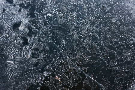 Cracked ice, snowflakes, snow, dark water surface, frozen lake shore. texture, close-up. picturesque winter scenery. Concept image, graphic resources. Nature, ecology, climate change, global warmingの写真素材
