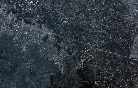 Cracked ice, snowflakes, snow, dark water surface, frozen lake shore. texture, close-up. picturesque winter scenery. Concept image, graphic resources. Nature, ecology, climate change, global warmingの写真素材