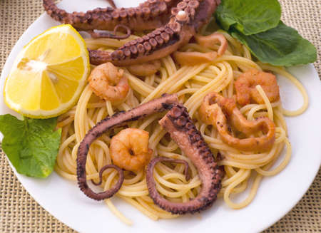 Pasta with seafood: octopus, squid and shrimp, decorated with lemon and herbsの写真素材