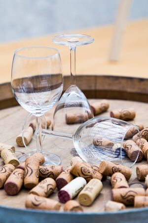 Wine glasses surrounded by bottle stoppers standing on a barrel