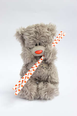 Grey teddy bear holding two straws with hearts on the white background isolatedの写真素材