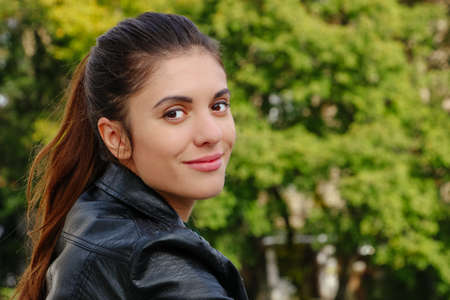 Brunette girl with pony tail long hair in leather jacket outdoorの写真素材