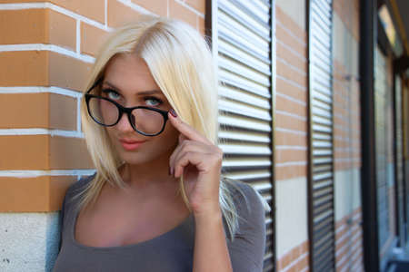 Teacher beautiful girl in glasses on the brick wall background in perspectiveの写真素材