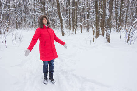 Portrait of a nice senior woman in the winter snow wood in red coatの写真素材