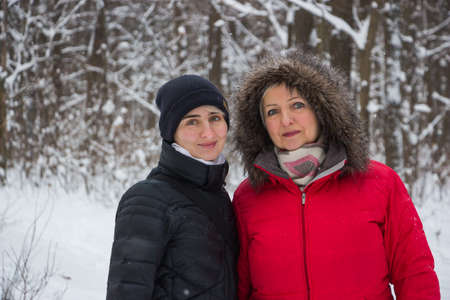 senior woman mother with daughter in winter in the snow wood smilingの写真素材