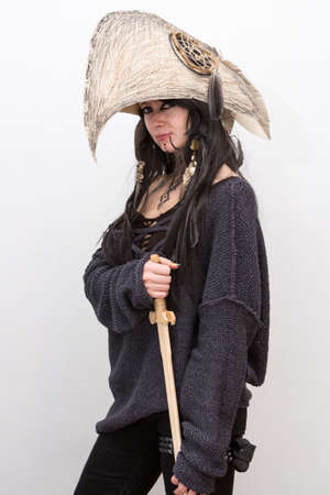Beautiful girl dressed in witch or shaman halloween costume with black feathers and crow head on the white background with shadowsの写真素材