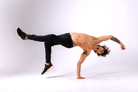 Strong powerful boy, man - freerunner, acrobat, tricker with muscular body in a jump upside down on a white backgroundの写真素材