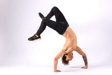 Strong powerful boy, man - freerunner, acrobat, tricker with muscular body in a jump upside down on a white backgroundの写真素材