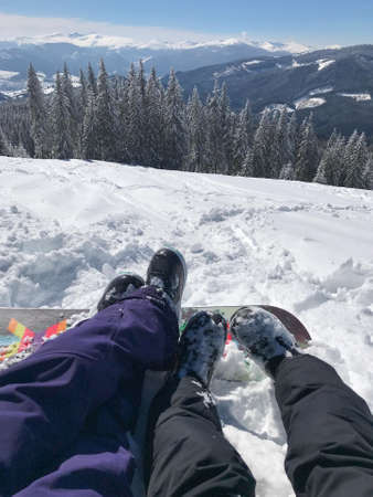 Leisure vacation in mountains on the ski report. Legs of the couple boy and girl in front of the beautiful snow mountains view.の写真素材