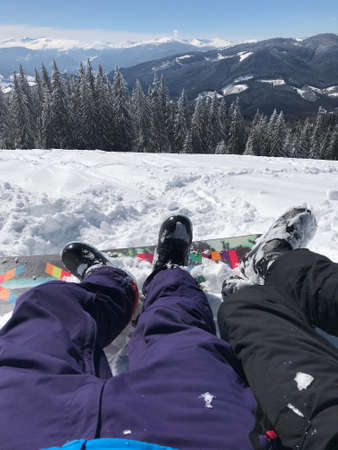 Leisure vacation in mountains on the ski report. Legs of the couple boy and girl in front of the beautiful snow mountains view.の写真素材