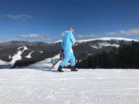 Girl in blue, pink unicorn pajama kigurumi outdoor with snowboard on the ski report in snow mountains.の写真素材