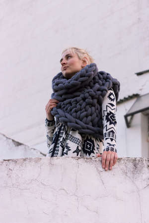 Blonde young beautiful fashion girl wearing aztec black and white jacket and knitted grey vest scarf. Festival outfit. Lifestyle street fashion trendの写真素材