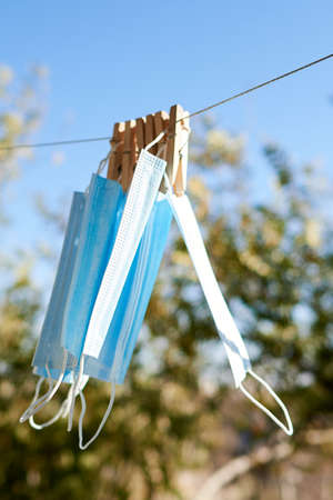 Sunlit face masks are hung to dry for disinfection fastened by wooden clothespins. New normal...