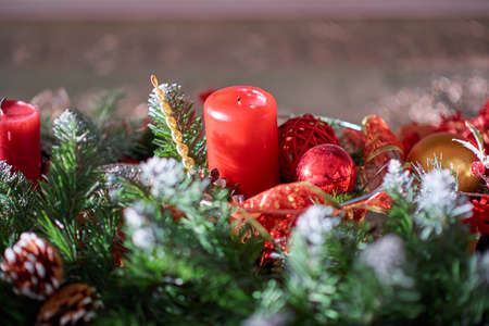 Red holiday candle among artificial spruce branches and Christmas tree decorations