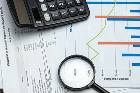 Single Magnifying Glass with calculator, Leaning on the financial data. Business and Finance conceptの写真素材