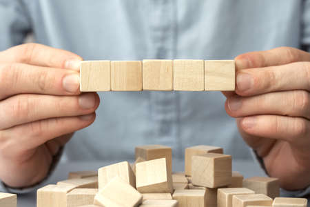 Cropped view of man holding an empty wood block on table. Business concept for growth success process. Copy space.の写真素材