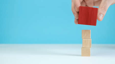 Hand arranging wood block stacking as step stair on wooden table. Business concept for growth...