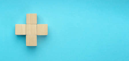 wooden blocks in the form of a cross on blue background. Success, medicine, win, victory, development or top ranking conceptの写真素材